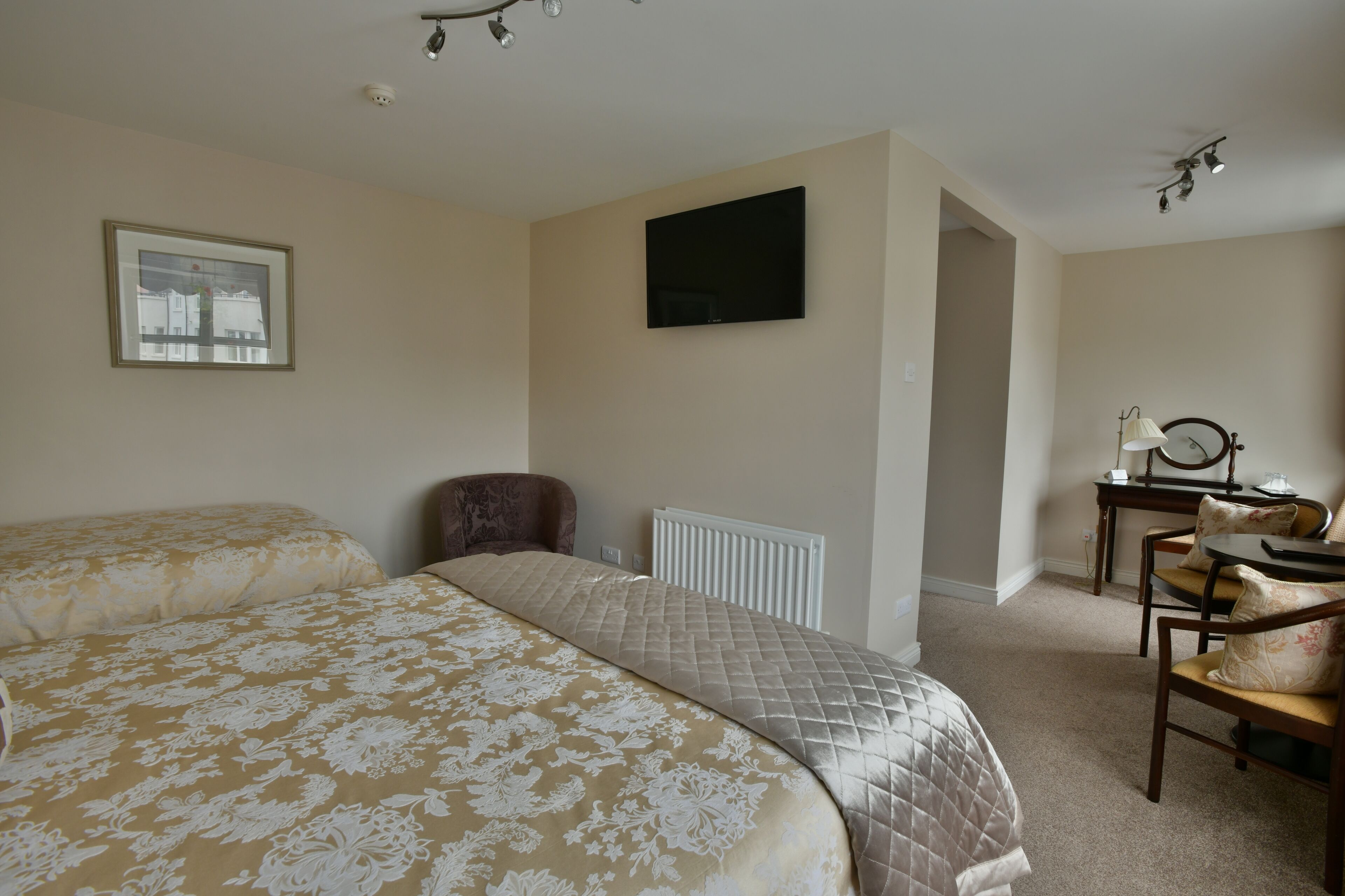 A hotel room with two beds, a desk with a chair, a television, and a framed picture on the wall.