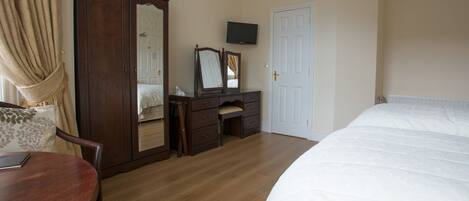 A bedroom with a bed, a dresser with a mirror, a television, and a door.
