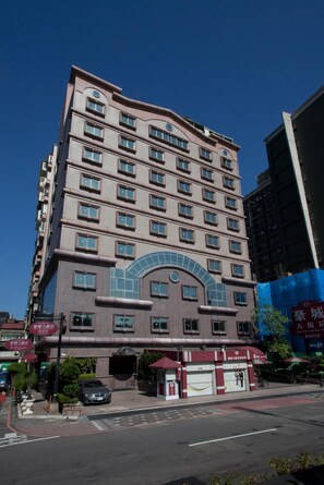 Ein mehrstöckiges Hotel mit markantem Bogenportal und zahlreichen Fenstern.