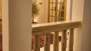 A corridor with a marble balustrade, a potted plant, and a large arched door. - Ca' Dei Polo (Venice)