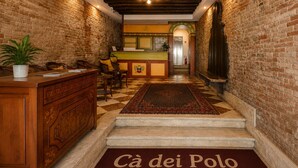 A lobby with a checkered floor, a reception desk, and a staircase leading to an upper level. - Ca' Dei Polo (Venice)