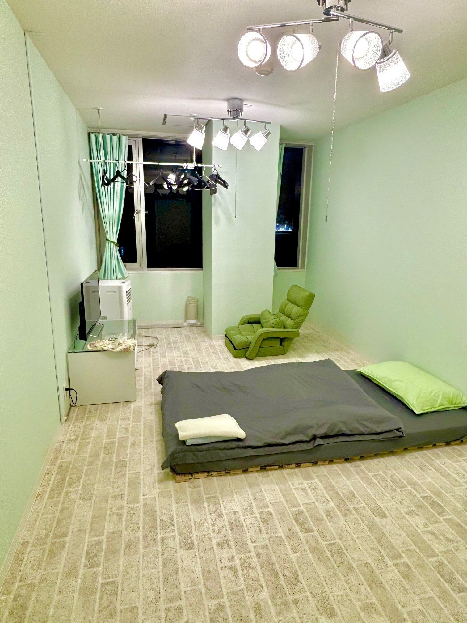 A room with a bed, a chair, a window, and a ceiling light fixture.