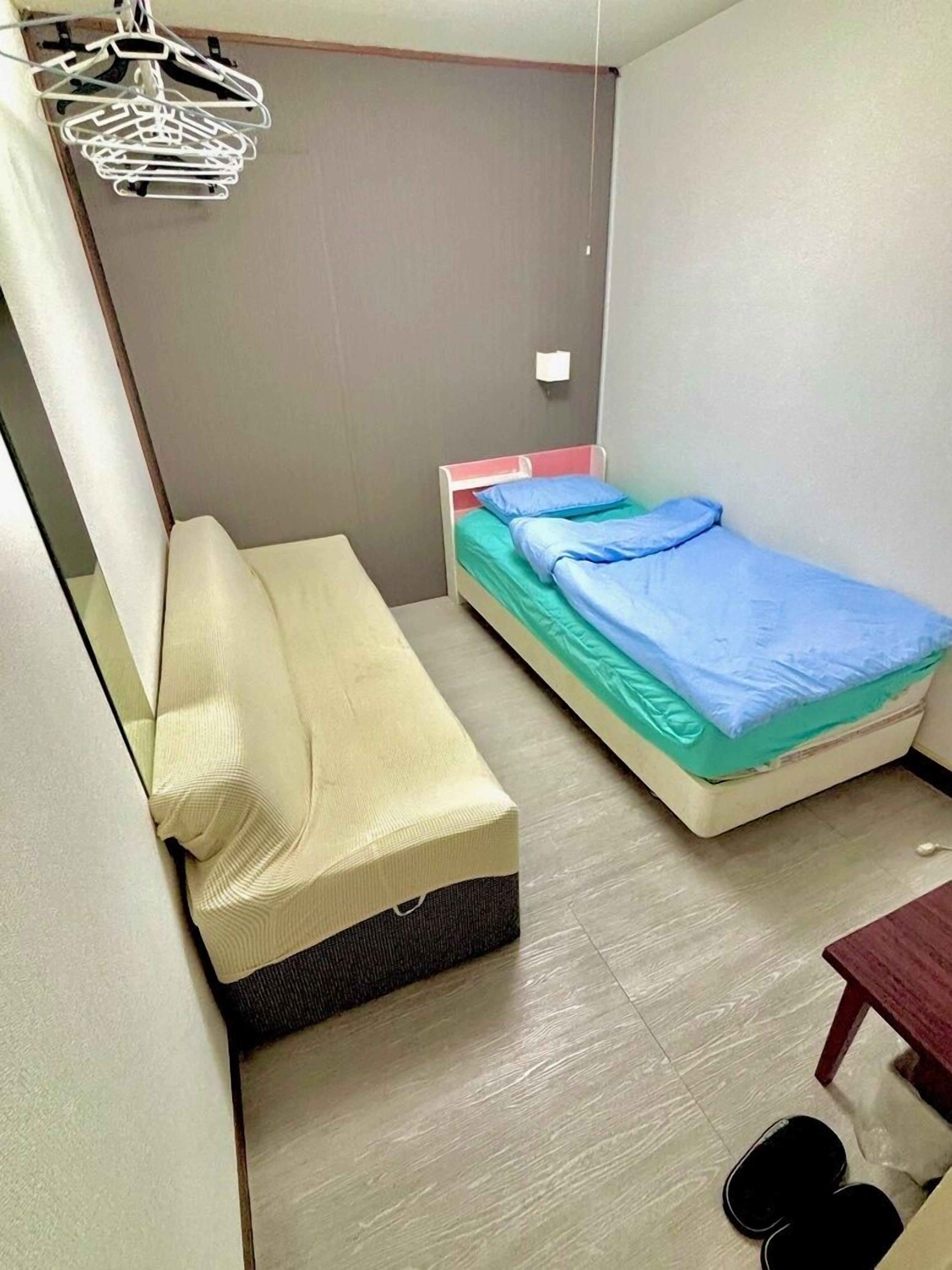 A small, compact room with a single bed, a sofa, and a small table.