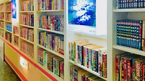 A library with bookshelves filled with books, a large illuminated poster, and a red carpeted floor. - Hotel Hoshi Kai Kan (Tokyo)