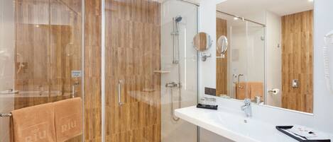 A modern bathroom with a glass-enclosed shower, wooden paneling, a white sink, and a large mirror.