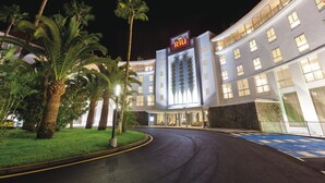 A hotel with a modern facade, palm trees, and a well-lit entrance. - Hotel Riu Arecas - Adults Only (Adeje)