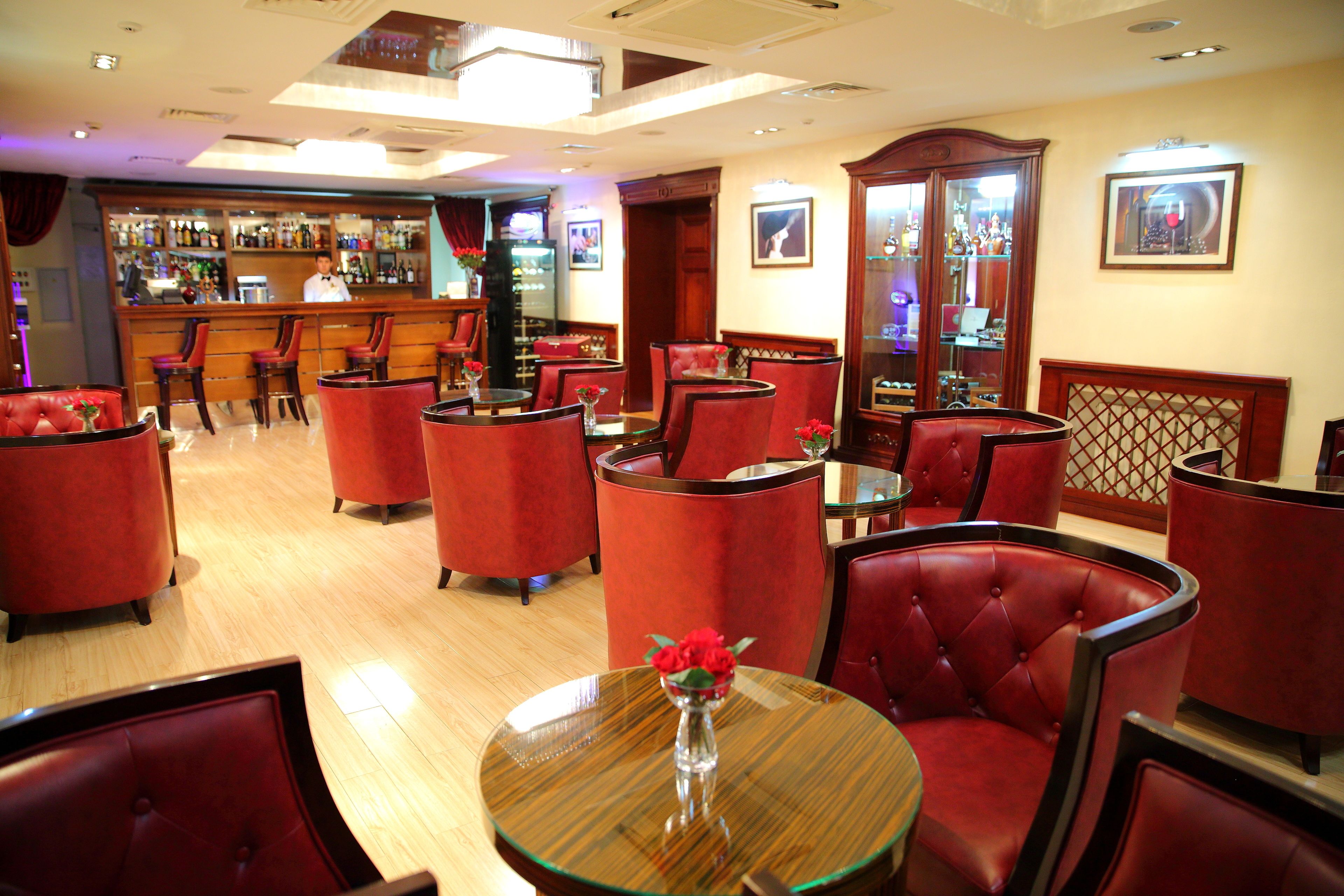 A bar area with red upholstered chairs and a wooden bar counter.