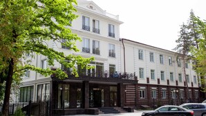 Een hotel met meerdere verdiepingen, met een klassiek architectuurontwerp, met een opvallende ingang met een zwarte luifel en een bord waarop 