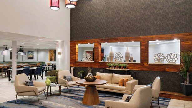A lobby with a sofa set, a coffee table, and a dining area in the background. - Fairfield Inn & Suites by Marriott Denver Aurora / Parker (Aurora)