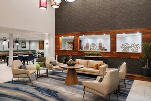 A lobby with a sofa set, a coffee table, and a dining area in the background.
