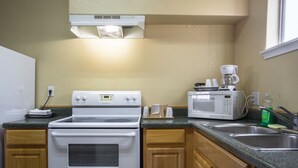 A kitchen with a stove, microwave, and coffee maker. - Pinn Road Inn and Suites (San Antonio)