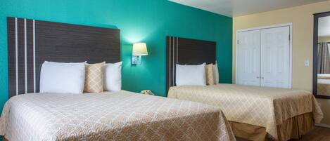 Habitación de hotel con dos camas, paredes color turquesa y piso de madera.