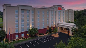 A Hampton Inn hotel with a modern facade, multiple floors, and a parking lot.
