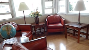 Un salon chaleureux avec des meubles en cuir, un globe terrestre, un vase rempli de fleurs et deux lampes.