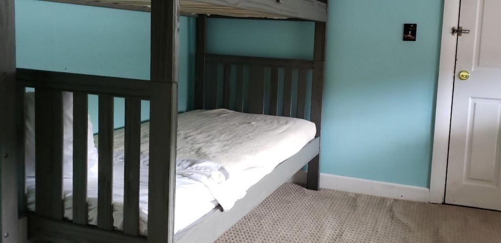 A bunk bed in a room with teal walls and a white door.