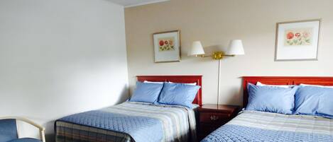 Une chambre d’hôtel avec deux lits, une chaise et deux tables de chevet avec des lampes.