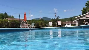 Une piscine avec un poste de surveillance pour sauveteur, un parasol rouge et un bâtiment portant l’inscription « FERMÉ ».