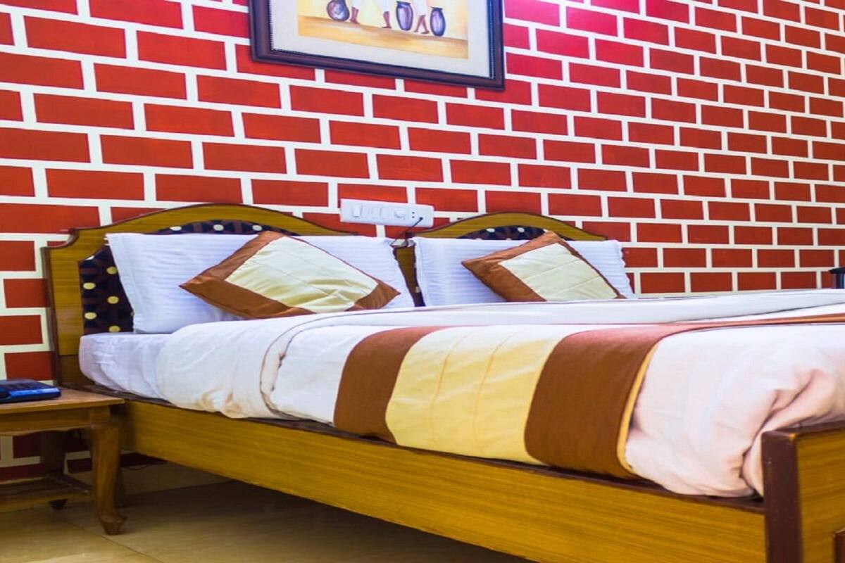 Ein Einzelbett mit Holzrahmen und einem gestreiften Bettbezug, ein Nachttisch mit Lampe und eine Wand mit Ziegelmuster.