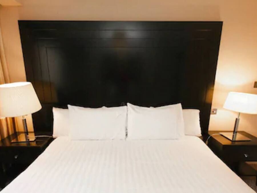 Ein Hotelzimmer mit einem großen Bett, zwei Nachttischen mit Lampen und einem dunklen Kopfteil.