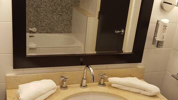 A bathroom with a double sink, a large mirror, and a tiled shower area.