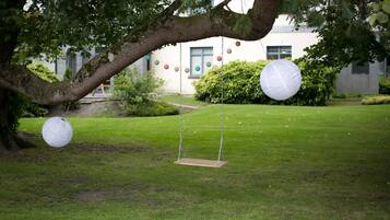 A grassy area with a swing set and hanging paper lanterns.