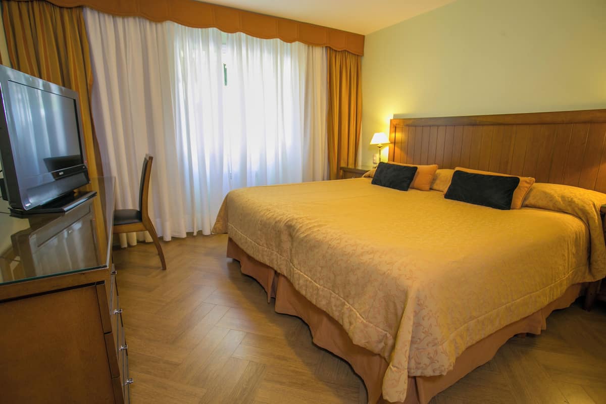 A hotel room with a bed, a TV, a chair, and a lamp.