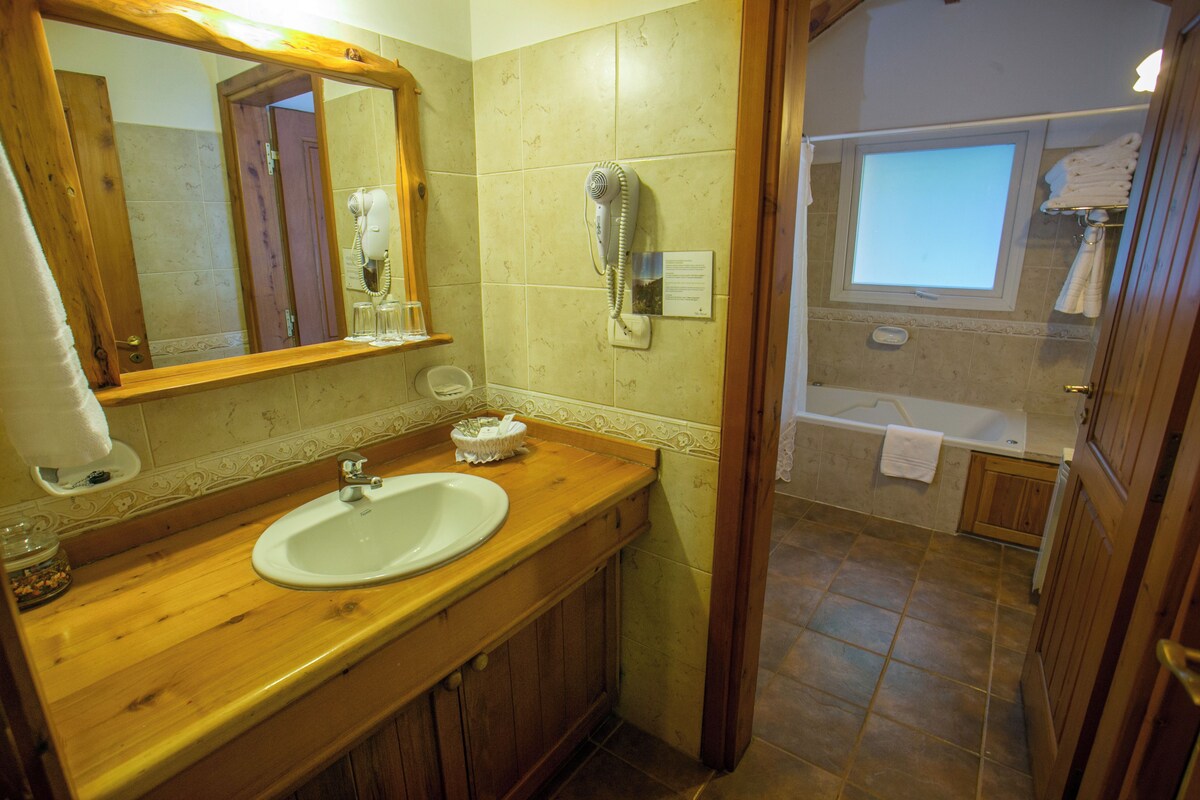 A bathroom with a wooden vanity, a sink, a hairdryer, and a window.