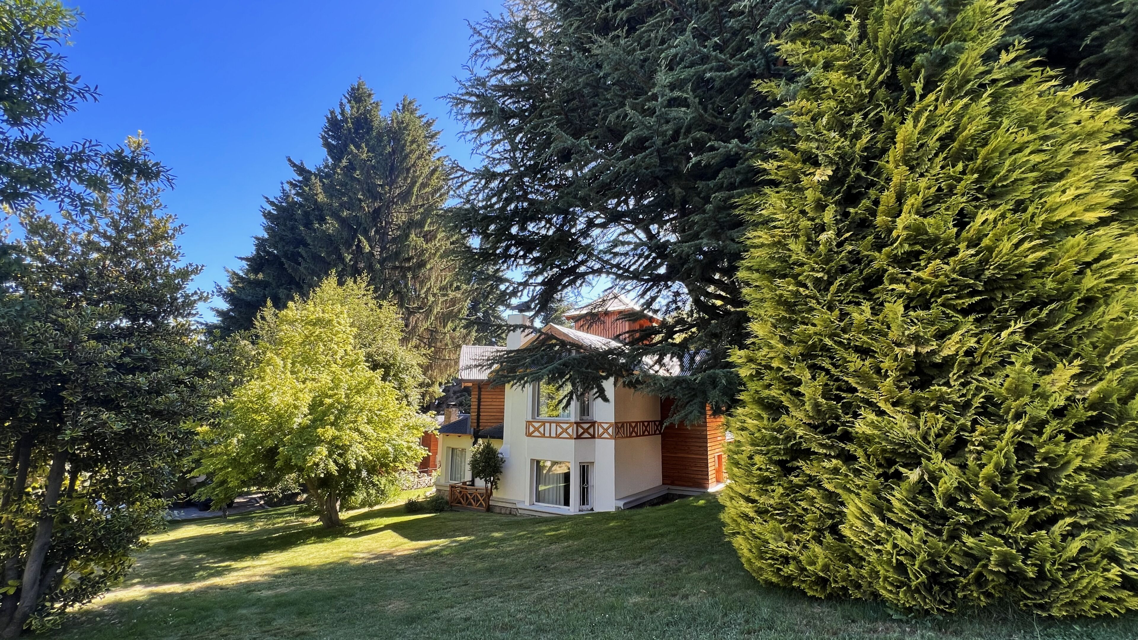Une maison avec un toit en pente, entourée d’arbres à feuilles persistantes et d’une pelouse bien entretenue.