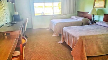 Une chambre d’hôtel avec un bureau, deux lits, une chaise, une fenêtre et une lampe.
