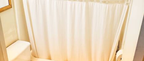 A small bathroom with a toilet, a bathtub, and a shower curtain.