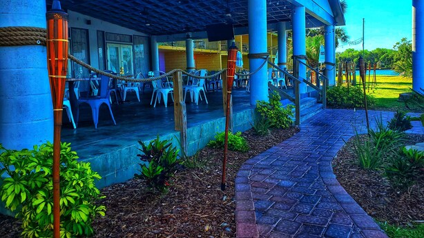 Zona esterna con tavoli e sedie, un vialetto e vista su una piscina.