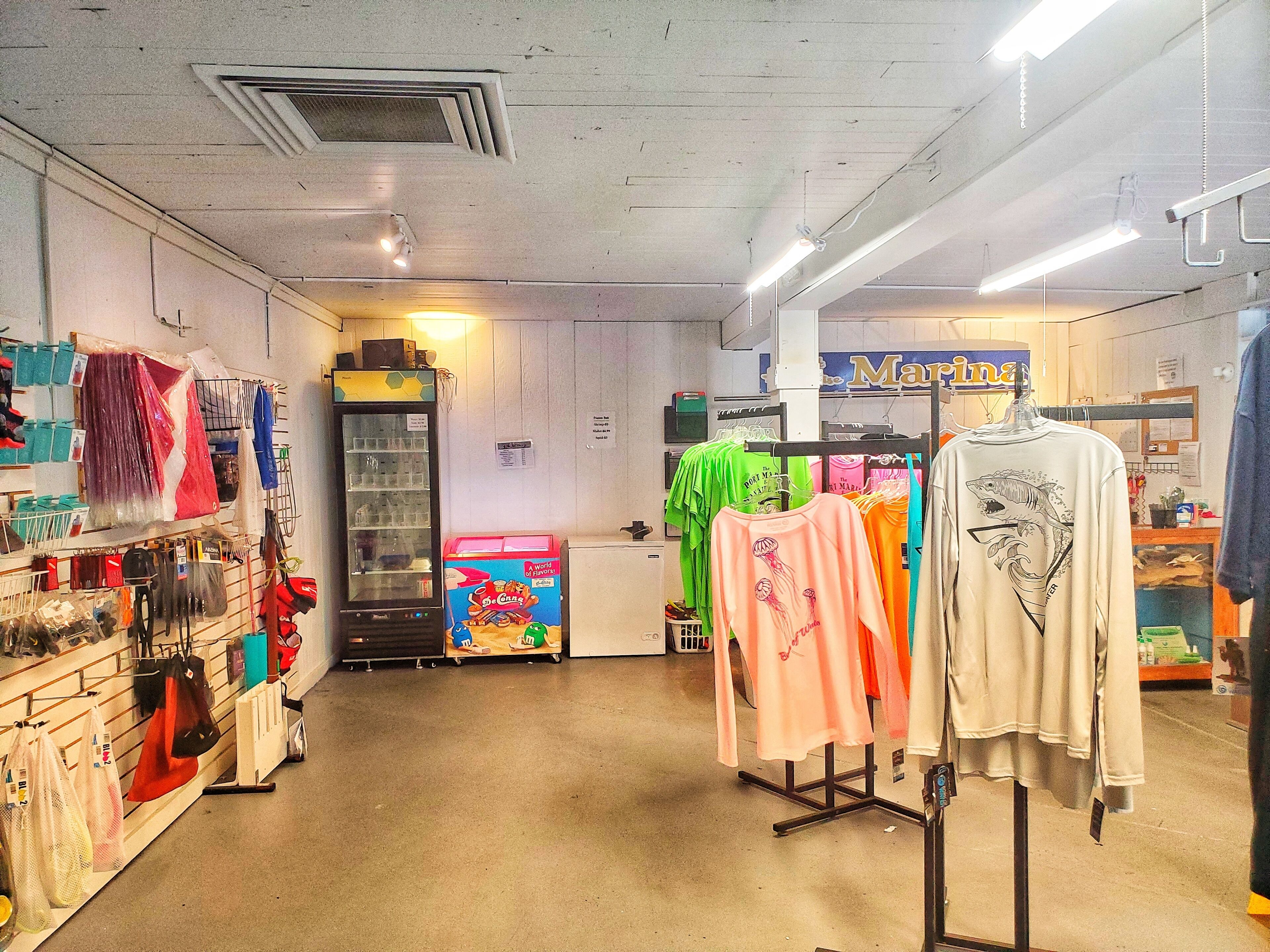 A clothing store with racks of clothes, a vending machine, and a sign for 'Marina'.
