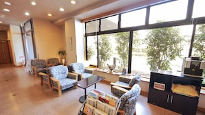 A spacious lobby with a seating area, large windows, and a reception desk. - Hotel Route-Inn Nagaizumi Numazu Inter 2 (Nagaizumi)