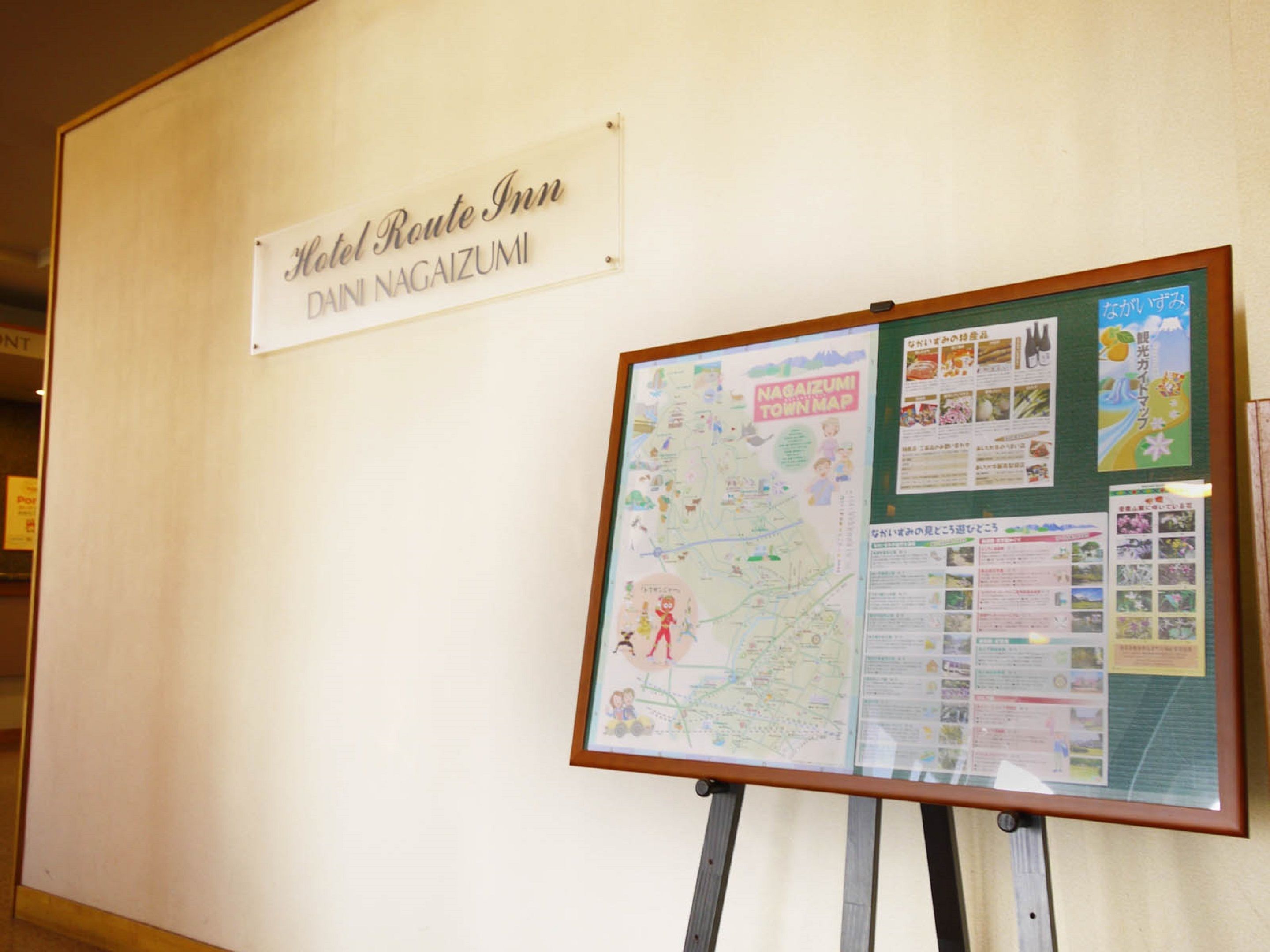 A wall with a sign for Hotel Route Inn and a large informational board with a map and various notices.