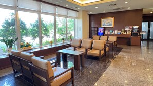 A lobby with seating, a reception desk, and a large window offering a view of greenery. - Hotel Route-Inn Omaezaki (Omaezaki)