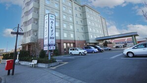 A hotel with multiple floors, a parking lot, and a clear sky. - Hotel Route-Inn Omaezaki (Omaezaki)