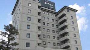 A multi-story hotel with a prominent sign in Japanese, balconies on the upper floors, and a parking area in front. - Hotel Route Inn Shimada Ekimae (Shimada)