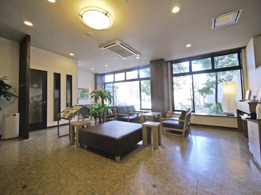 A spacious lobby with a reception desk, seating area, and large windows providing natural light.