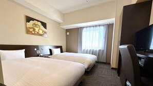 Ein Hotelzimmer mit zwei Betten, einem Fernseher, einem Schreibtisch und einem Bild an der Wand.