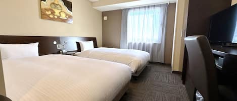 Habitación de hotel con dos camas, televisión, escritorio y un cuadro en la pared.