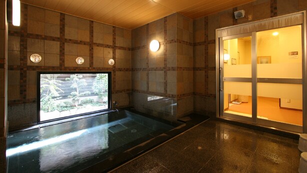 Ein Spa-Raum mit einer großen Badewanne, einem Fenster mit Blick auf Grünflächen und einer Schiebeglastür, die zu einem Badezimmer führt.