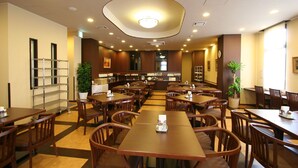 Ein geräumiges Restaurant mit mehreren Holztischen und -stühlen, einer zentralen Serviereinsel und einer Decke mit Einbuchtungslichtern.