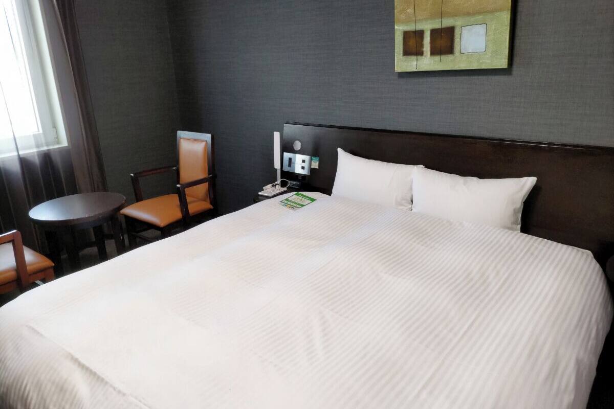 Habitació d'hotel amb un llit gran, un escriptori, una cadira i una taula petita.