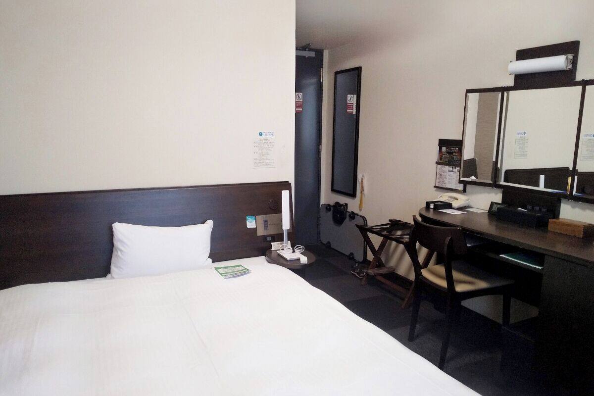 Habitació d'hotel amb un llit gran, un escriptori amb un ordinador i una cadira.