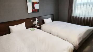 A hotel room with two beds, a nightstand with a lamp, a wall-mounted artwork, and a window with curtains.