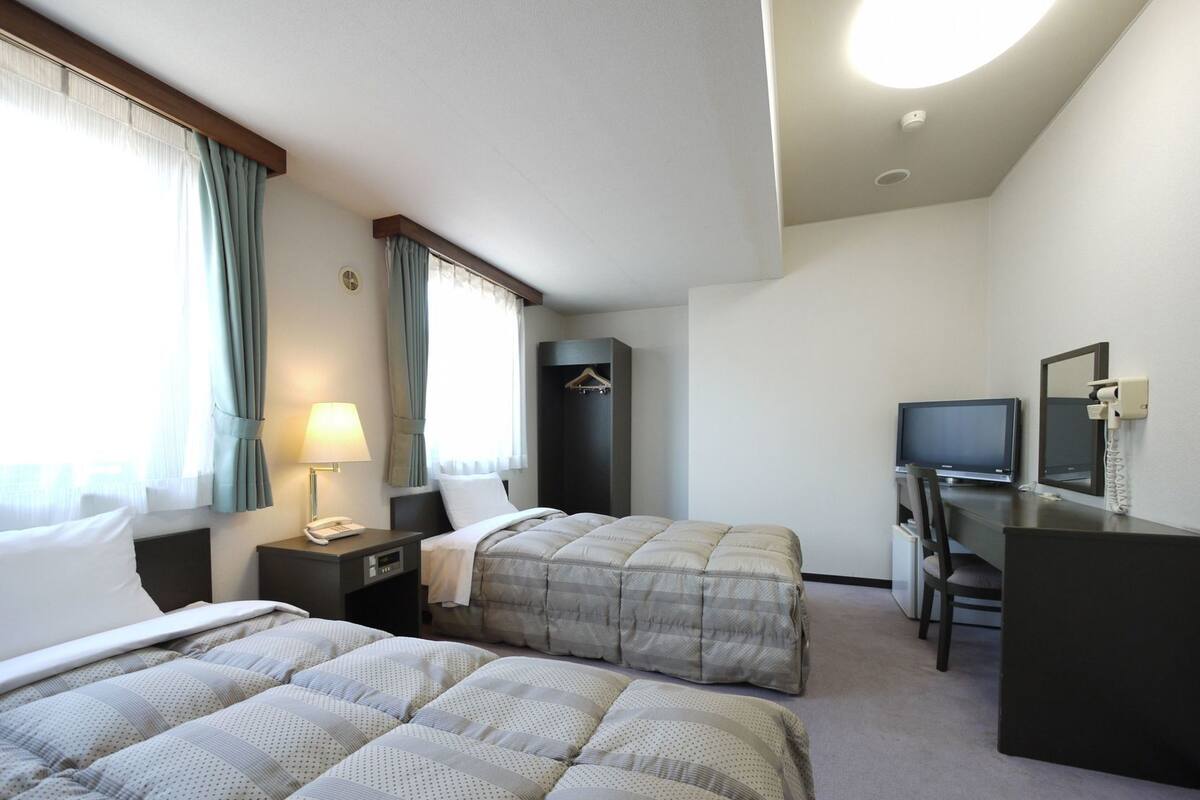 Ett hotellrum med två sängar, ett skrivbord, en tv och en garderob.
