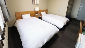 A hotel room with two beds, a wooden headboard, a bedside table with a lamp, and a small desk with a telephone. - Hotel Route Inn Kani (Kani)