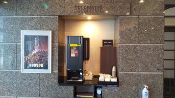 A self-service coffee station with a coffee machine, a sign for the self-cafe, and a poster advertising a doctor.