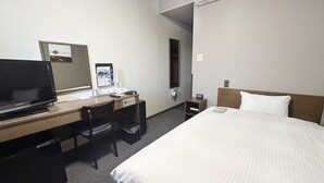 A hotel room with a bed, a desk with a computer, a chair, a small table, and an air conditioning unit. - Hotel Route Inn Minokamo (Minokamo)