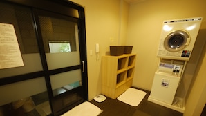 A laundry room with a washing machine, a drying machine, and a wooden shelf with baskets. - Hotel Route-Inn Nakatsugawa Inter (Nakatsugawa)